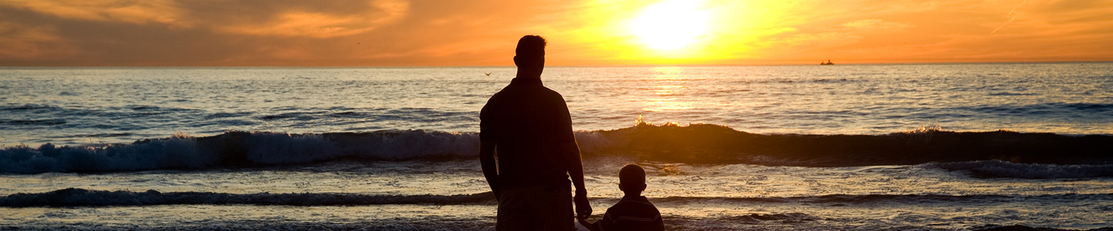 man and child watching sunset